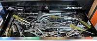 Drawer filled with assorted hand tools including wrenches, screwdrivers, and sockets in a Husky branded metal tool drawer