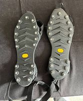 Rubber soles with multiple metal spikes arranged symmetrically and yellow Vibram logo