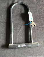 Photo of Mountain Equipment Co-op U-lock bike lock placed on black fabric, showing lock and keys attached with blue tie.