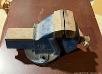 Angle view of the blue metal bench vice showing jaws and 'Made in England' marking on the body.