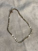 Full view of the 14kt gold anklet or bracelet laid flat on fabric background showing the clasp and chain design.