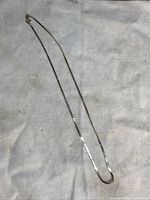 Full-length view of serpentine chain with clasp laid flat on white cloth