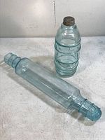Antique aqua glass rolling pin and glass jar with zinc cap displayed on a white surface, showing their size and condition.