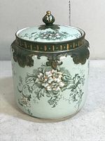 Porcelain biscuit jar with lid, showing detailed floral decoration and green/gold accents from various angles.