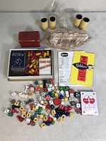 Photo showing assorted vintage board game pieces including dice, pawns, letter tiles, game cards, and instruction sheets