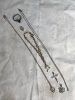 Full lot showing several gold filled necklaces, bracelet with boot charm, ring, and pendants on light background.