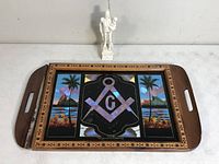 Photo of wooden souvenir tray with integrated colorful tropical scene and Masonic emblem, showing one side handle loose.