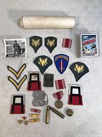 Photo showing the majority of items laid out including patches, medals, pins, dog tags, bullet casings, photos, and collectible cards