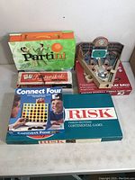 Photo showing all five games included in lot: Partini, Rummikub, Connect Four, Risk, and vintage baseball pinball game.