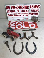 View of various metal items showing horseshoes, spurs, tractor toy, no trespassing and sold signs, pencil sharpener.