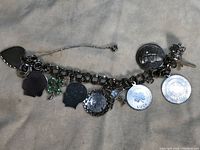 Full view of the charm bracelet showing the variety of attached charms including heart, silhouettes, clover, coins.