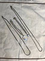 Four sterling silver items laid out on fabric, showing necklaces and bracelets with pendants.