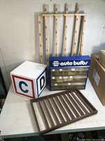 Four retail store display items on table including wooden slatted wall hanging display, NAPA auto bulbs countertop display, and two cube-shaped displays with letters 'C' and 'D'.