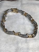 Full view of bracelet laid flat on white surface showing alternating yellow and white gold links