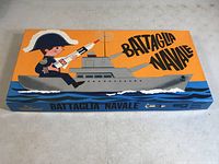 Top view of the game box showing the bright orange lid featuring a cartoon naval officer on a battleship with the title 'Battaglia Navale'.