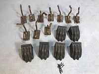 Full lot laid out on white surface showing 10 brass coat hangers with bent hooks and 6 claw foot covers plus mounting nails.