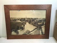 Full front view of rectangular oak frame with quarter sawn grain and sepia 1909 photo print showing river and church steeple, minor damage and dust visible