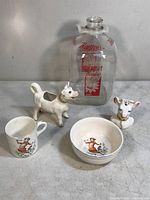 Photo showing all 5 items: glass milk bottle, cow creamer figurine, cow head vase, cup, and bowl with Elsie cow illustrations