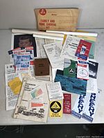 Photo showing an assortment of vintage government survival items including Family and Home Survival Kit envelope, pamphlets, flyers, stickers, and folded posters.