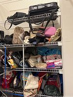 Shelf filled with various purses, bags, totes, and reusable shopping bags in multiple colors and patterns, showing general condition and variety in the lot.