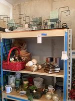 Shelf of assorted baskets, planters, bookends, mugs, and decorative items