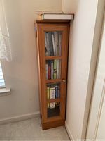 Front view of the wooden bookcase showing glass door with four window panes and books inside.