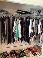 Wide view of the closet rack showing a variety of pants, shirts, and dresses hung neatly with shoes lined below.