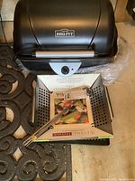 Black Crock Pot BBQ Pit slow cooker with control knob, perforated metal grill plate, and metal skewers visible on top.