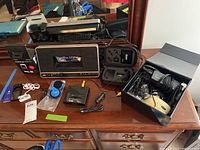 Photo of all main items on brown wooden dresser including JVC charging dock, Apple iPods, phone mount, cables, and electronic accessories.