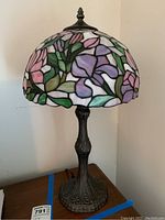 Photo showing the Tiffany style stained glass lamp from a side angle highlighting the floral stained glass shade and decorative metal base.
