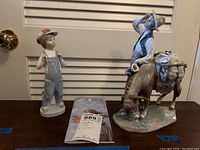 Photo showing both Lladro figurines and a brochure, with measurement labels on the table.