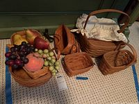 Photo of six baskets including one large with liner and assorted faux fruit inside and around baskets on carpeted floor
