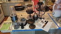 Full view of the Ninja and Nutribullet items arranged on a countertop showing blender bases, cups, lids, blade assemblies, and manuals.
