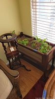 Shows both plant stands positioned by a window and a wall with hardwood floor. The rectangular planter stand is filled with faux green vines.