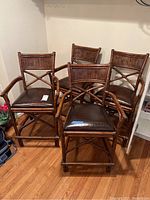 Four matching rattan stools with brown faux leather crocodile-patterned cushions placed on a wooden floor.