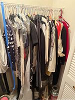 Photo showing a rack of women's clothing items including wool coats, dresses, and tops in various sizes and colors.
