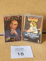 Two Bob Marley audio cassette tapes, 'Legend' and 'Bob Marley and The Wailers Live!', in clear plastic cases with cover art featuring Bob Marley.