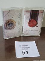 Two Whitesnake audio cassette tapes in plastic cases side by side on a wooden surface, showing front cover artwork for the albums Whitesnake and Slip of the Tongue.