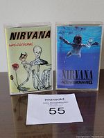 Front view of two Nirvana cassettes, In Utero and Nevermind, placed side by side in clear plastic cases.