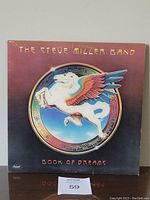 Front cover of The Steve Miller Band 'Book of Dreams' vinyl album showing artwork with flying Pegasus horse icon.