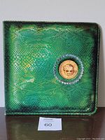 Front side of the green snakeskin-textured gatefold vinyl album cover with an embedded gold coin emblem featuring Alice Cooper's face.