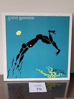 Front cover of Steve Winwood 'Arc of a Diver' vinyl LP showing abstract diver artwork on blue background with yellow sun and stylized text.