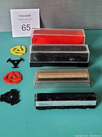 Photo of four vintage microfiber record cleaners with red and black cleaning surfaces, a Koss-branded antistatic cleaner, and 45 RPM inserts in various colors.