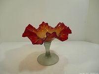 Side view of the stem bowl showing the ruffled red and yellow top and the clear stem and foot.