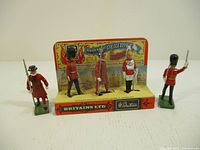 Five metal soldier figures by Britains Ltd displayed on and near original cardboard stand