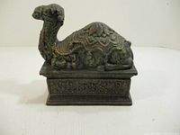 Front view of the cast iron camel figurine showing intricate pattern details on the body and base.