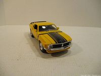 Front view of yellow Ford Mustang Boss 302 die cast model showing black hood stripes and Mustang emblem on grille.
