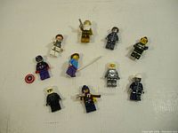 Top-down image showing 10 assorted LEGO minifigures laid out on a white surface