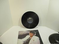 Vinyl record shown standing up and album cover laid flat in front of it.
