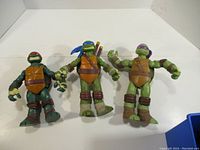 Three Playmates Teenage Mutant Ninja Turtles action figures displayed side by side on a white background, showing overall condition and size.